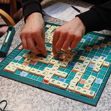 Prawie stu graczy zasidzie przy stolikach scrabble