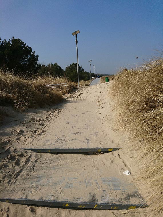 Kładka wzdłuż wydm pełna piasku, niczym plaża. Czytelniczka przesłała zdjęcie